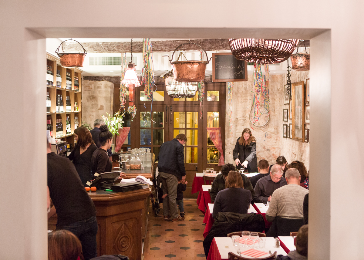 Salle du restaurant, cuivres suspendus et murs de pierre